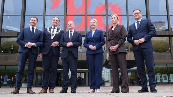 Michael Kretschmer (CDU, l-r, Ministerpräsident des Landes Sachsen, Burkhard Jung (SPD), Oberbürgermeister der Stadt Leipzig, Olaf Scholz (SPD), Bundeskanzler, Manuela Schwesig (SPD), Ministerpräsidentin des Landes Mecklenburg-Vorpommern in ihrer Funktion als Bundesratspräsidentin, Ayleena Jung, Ehefrau des Leipziger Oberbürgermeisters, und Carsten Schneider (SPD), Ostbeauftragter der Bundesregierung, stehen vor dem Gewandhaus in Leipzig.