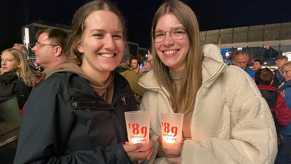 Zwei junge frauen stehen in der Leipziger innenstadt und freuen sich, dass sie beim Lichtfest mit an die Friesdliche Revolution erinnern können.