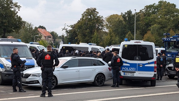 Einsatzkräfte und -fahrzeuge der Polizei stehen auf einem Platz.