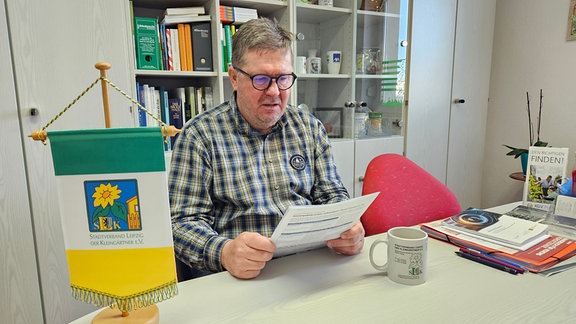 Ein Mann mit Brille liest ein Dokument.