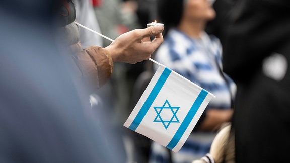 Ein Teilnehmer einer Kundgebung im Zentrum der Stadt hält eine Kerze und eine israelische Fahne in seiner Hand