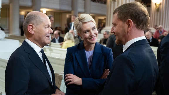 Bundeskanzler Olaf Scholz (SPD, l-r), Manuela Schwesig (SPD), Bundesratspräsidentin und Ministerpräsidentin von Mecklenburg Vorpommern, und Michael Kretschmer (CDU), Ministerpräsident von Sachsen, stehen vor Beginn einer Andacht in der Nikolaikirche zusammen.