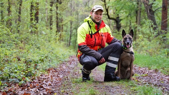 Ein Mann und ein Rettungshund schauen in die Kamera. 