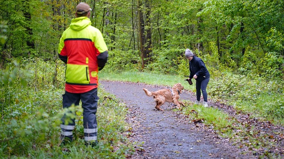 Eine Frau übt mit ihrem Hund Aportieren. 