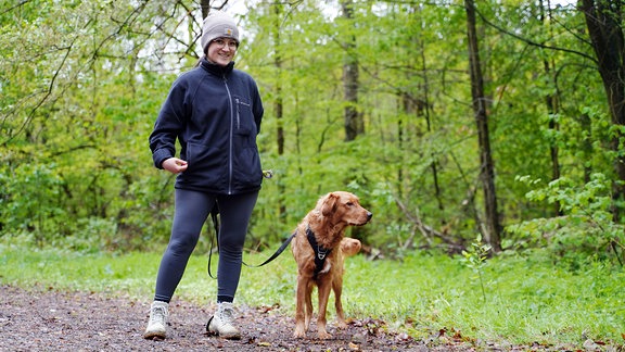 Eine Frau mit Hund lächelt in die Kamera. 