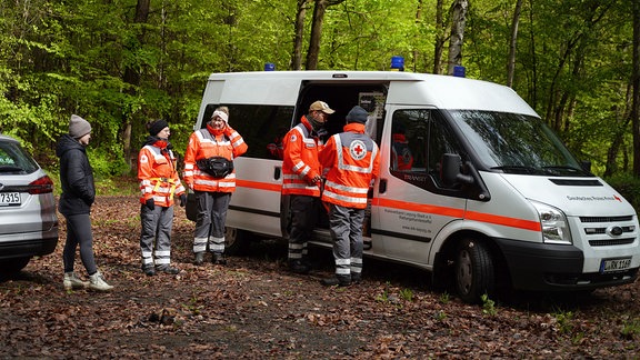 Mitglieder der DRK-Rettungshundestaffel vor einem Transporter.  