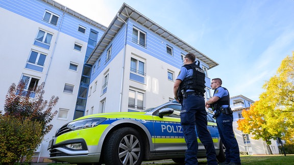 Polizisten stehen vor einem Mehrfamilienhaus in Leipzig. Ein sieben Jahre altes Mädchen ist in Leipzig an schweren Verletzungen gestorben. Nach ersten Erkenntnissen von Polizei und Staatsanwaltschaft soll die 13 Jahre alte Schwester des Mädchens die Verletzungen verursacht haben.