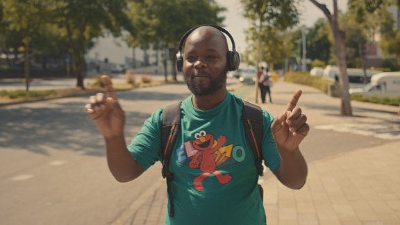 Schwarzer Mann hört mit Kopfhörern begeistert Musik.