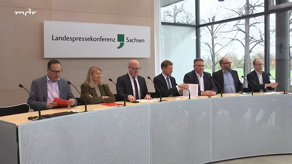 Politiker von SPD und CDU sitzen bei einer Pressekonferenz an einem Tisch.