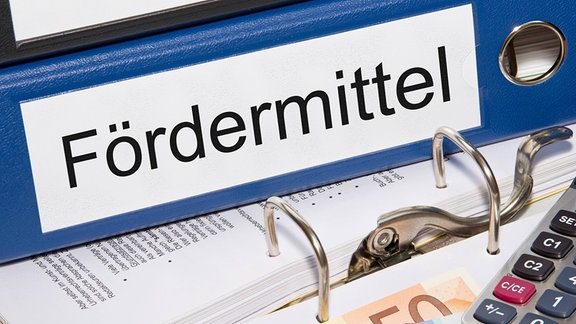 Auf einem Aktenordner steht "Fördermittel".