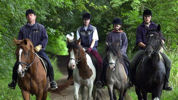 Eine Reiter*innengruppe unterwegs auf einem Reitweg