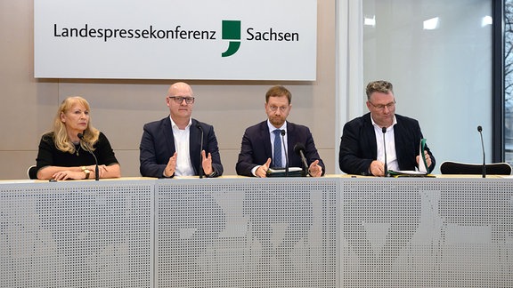 Petra Köpping (SPD, l-r), Henning Homann, Michael Kretschmer (CDU), und Christian Hartmann (CDU), sitzen während einer Pressekonferenz im Sächsischen Landtag auf dem Podium. 