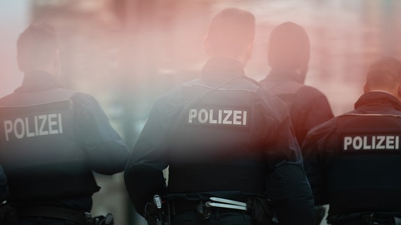 Polizisten stehen hinter einem Absperrband