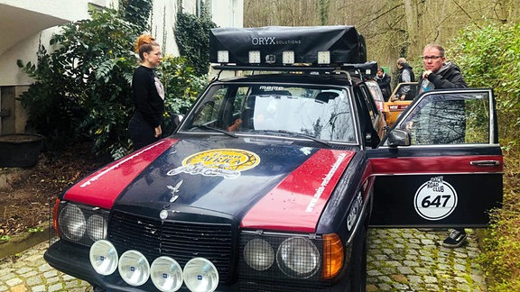 Ein Mann und eine Frau an einem für Offroad-Reisen vorbereiteten Auto