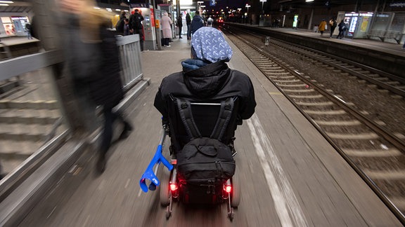 Steffen Gödecke fährt 2019 mit seinem Elektro-Rollstuhl im Bahnhof an einem Gleis.