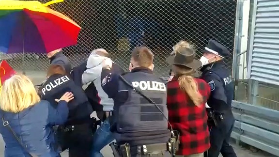 Mehrere Demonstranten umringen Polizisten.