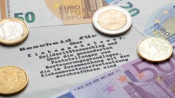 Geld liegt auf einem Einkommensteuerbescheid des Finanzamts.