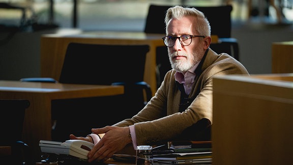 Ein Mann mit Brille und weißem Bart sitzt im Halbschatten im Thüringen Landtag.