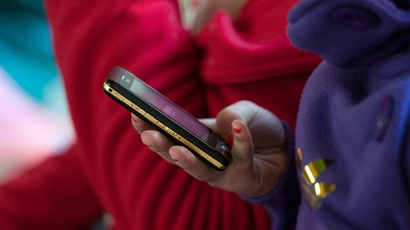 Eine Schülerin hält ein mobiles Telefon in der Hand. 