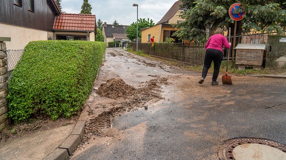 Eine Frau mit einer Schaufel neben einem Haufen Schlamm. 