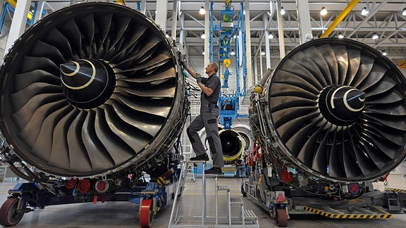 Ein Mann steht in einer Halle zwischen zwei Flugzeugtriebwerken