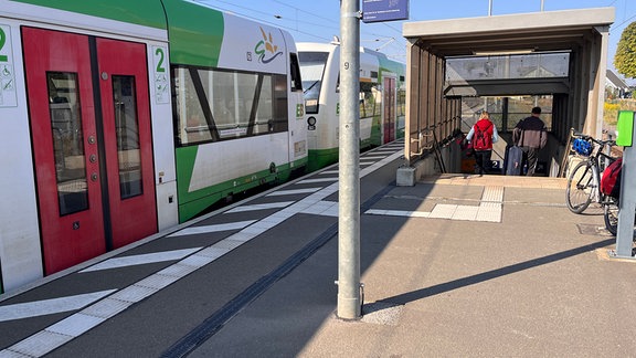 Reisende gehen eine Bahnhofstreppe hinab.