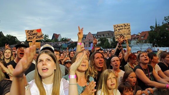 Eine Gruppe jüngerer Fans schaut zur Bühne und singt mit.