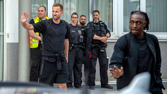 Zwei Fußballspieler grüßen im Vorbeigehen die Fans.