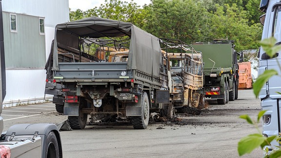 Abgebrannte Militär-Lkw stehen auf einem Hof.