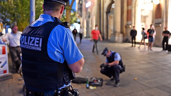  Polizisten kontrollieren eine Person am Anger. 