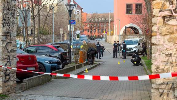 Polizisten untersuchen einen Gehweg.