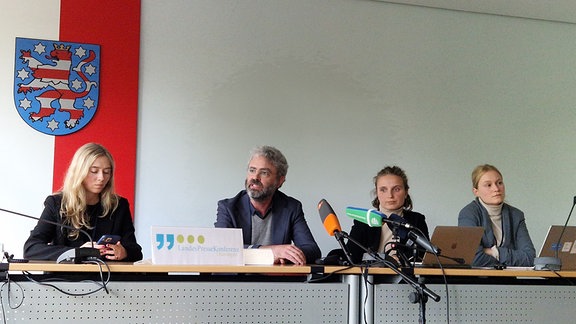 Menschen an einem Tisch bei einer Pressekonferenz