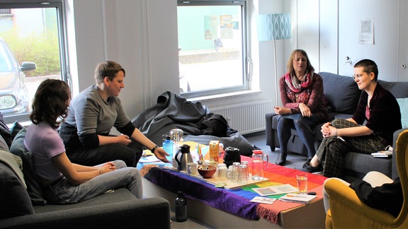 Menschen sitzen an verschiedenen Orten im queeren Zentrum in Erfurt und unterhalten sich.