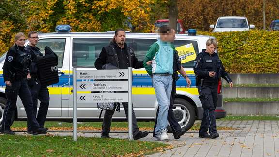 Ein Berufsschüler wird von der Polizei in Handschellen abgeführt