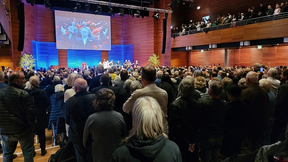 Stehend nehmen Trauergäste Abschied vom verstorbenen Weimarer Musiker Kani.