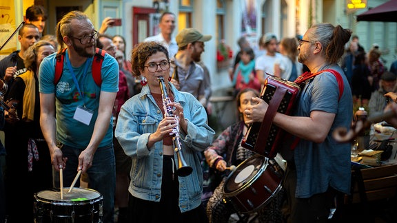 Jam-Session beim Yiddish Summer Weimar: Musiker ziehen mit Klarinette und Schlaginstrumenten durch eine abendliche Straße, ausgelassene Stimmung