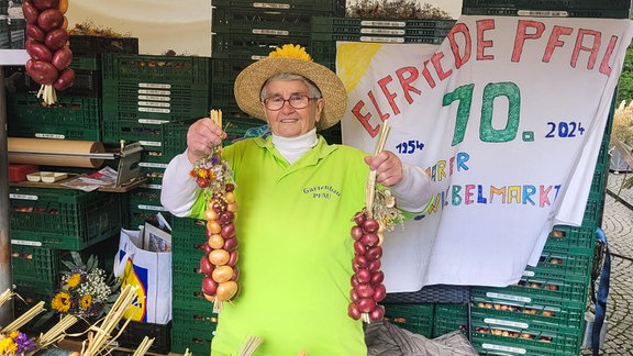 Elfriede Pfau mit Zwiebelzöpfen an ihrem Stand