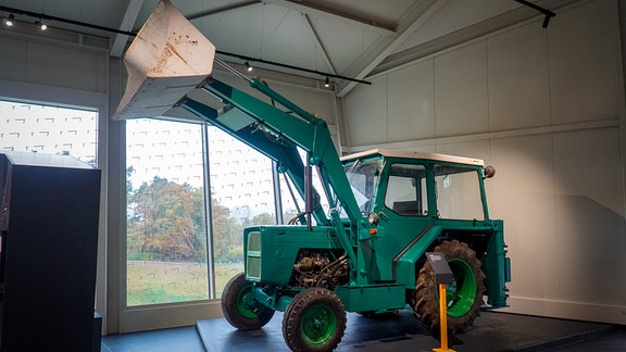 Ein grüner Radlader steht in einem Museum.