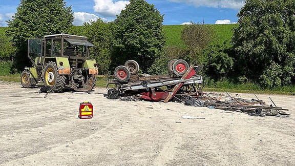 Ein umgestürzter Anhänger an einem Traktor liegt an der Unfallstelle.