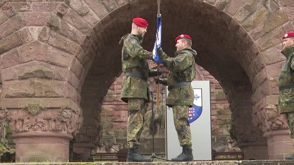 Ein Bundeswehrsoldat übergibt einem anderen Soldaten einen Kompaniewimpel.