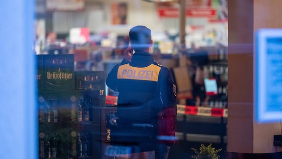 Ein Polizist steht nach einem Einbruch in einem Supermarkt.