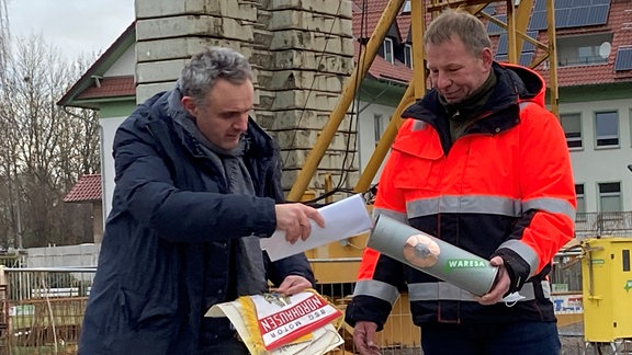 Zwei Männer verpacken Zeitkapsel