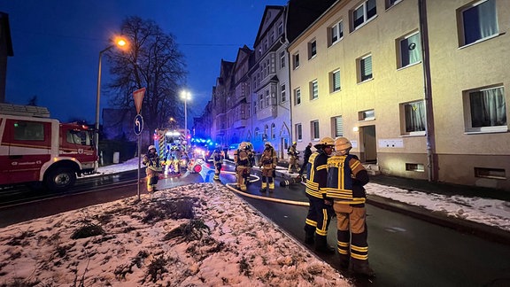 Feuerwehrleute bei Brandeinsatz an einem Mehrfamilienhaus