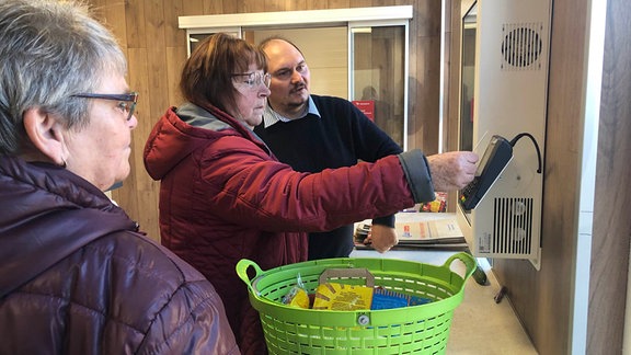 Drei Menschen an einer Kasse in einem 24-Stunden-Laden.