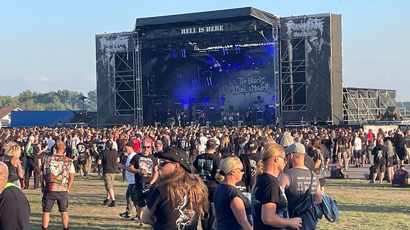 Heavy-Metal-Fans stehen vor einer großen Bühne.