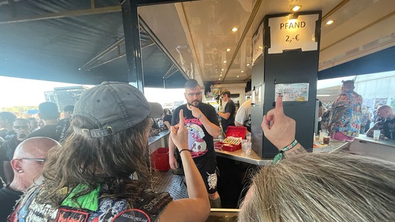 Menschen bestellen Getränke an einem Stand auf einem Festival.