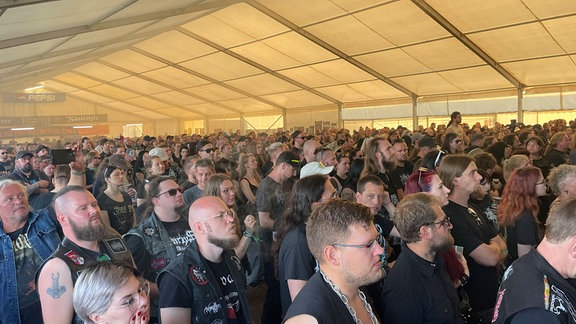 Heavy-Metal-Fans stehen in einem großen Zelt.