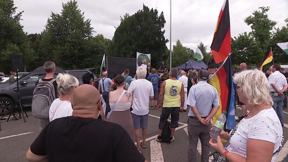 Demonstranten stehen vor einer Bühne.