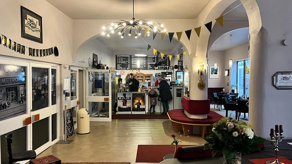 Panorama-Blick auf das Foyer des Kino Metropol: einladende Farben, rote Sitzgelegenheiten, im Hintergrund der Verkaufstresen. 