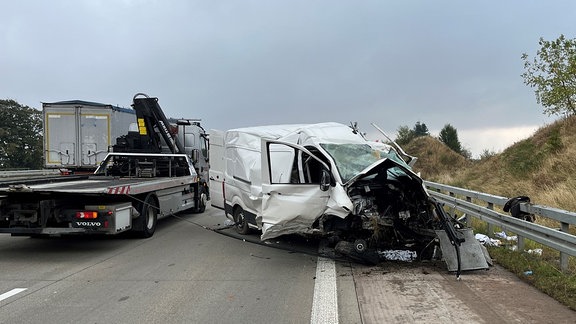 Ein kaputter, weisser Transporter liegt auf dem Dach.